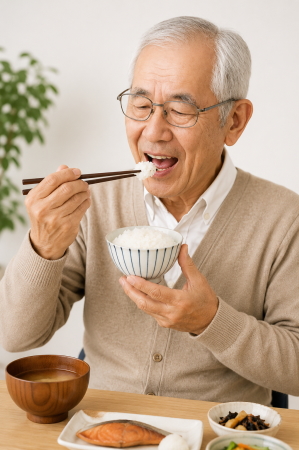金属床義歯を装着して美味しそうに食事をしている男性の写真。